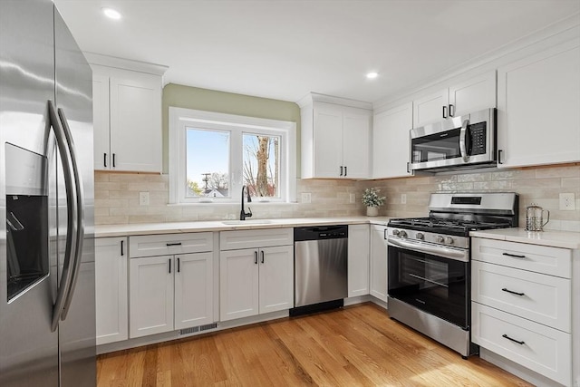 kitchen featuring light wood-style floors, a sink, appliances with stainless steel finishes, and light countertops