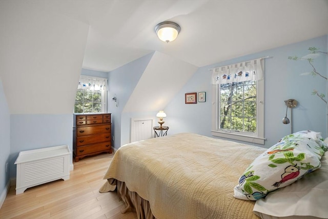 bedroom with multiple windows, light hardwood / wood-style flooring, and lofted ceiling