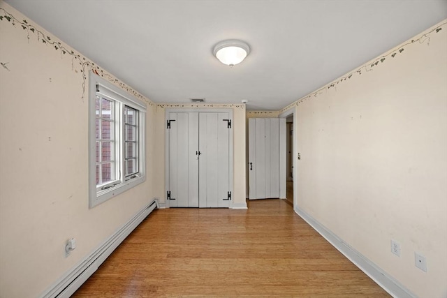 interior space with a closet, a baseboard heating unit, and light hardwood / wood-style flooring