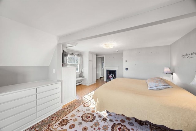 bedroom featuring lofted ceiling, a baseboard heating unit, and light hardwood / wood-style flooring