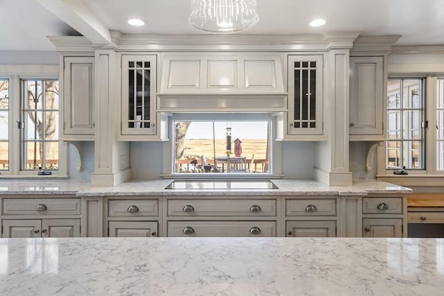 kitchen with a healthy amount of sunlight, black electric stovetop, and light stone countertops