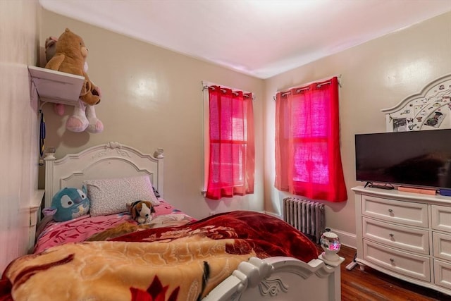 bedroom with radiator, baseboards, and dark wood finished floors