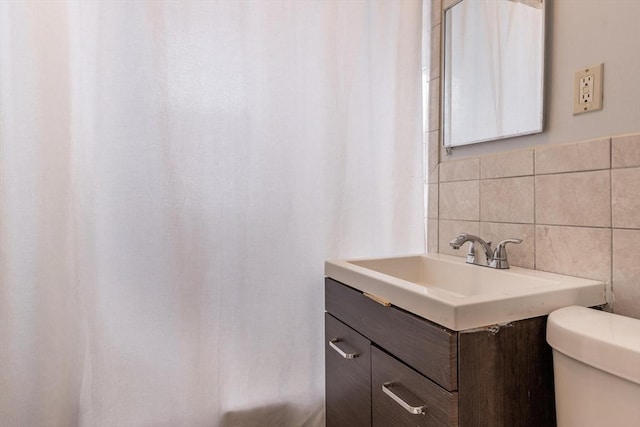 bathroom with toilet, decorative backsplash, tile walls, and vanity