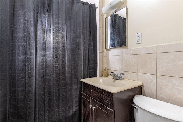 bathroom with curtained shower, tile walls, toilet, and vanity