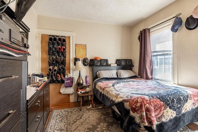 bedroom featuring a textured ceiling, multiple windows, and wood finished floors