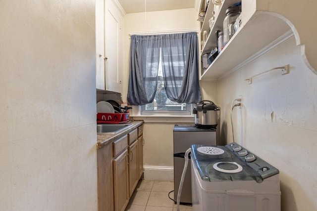 kitchen featuring light tile patterned floors, stove, a sink, and brown cabinetry