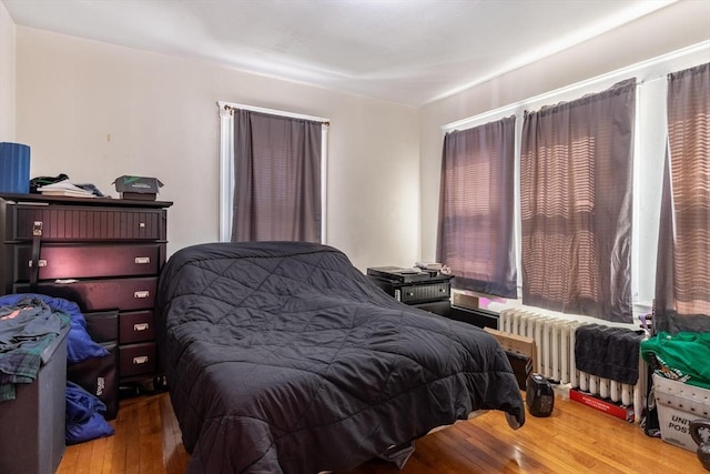 bedroom featuring radiator heating unit and hardwood / wood-style floors