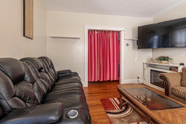 living room featuring a glass covered fireplace, baseboards, and wood finished floors