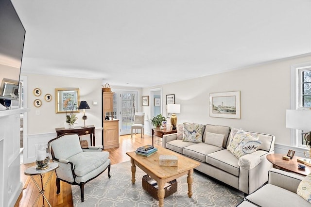 living room with ornamental molding, a fireplace, and light wood-style flooring