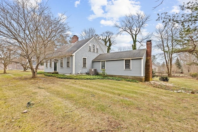 view of front of house with a chimney, a front lawn, central AC, and roof with shingles