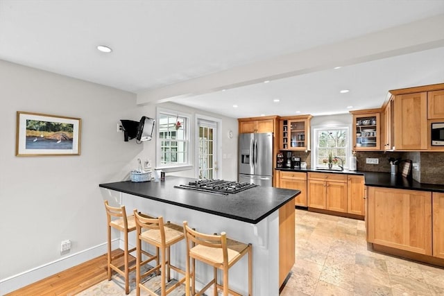 kitchen with a breakfast bar, stainless steel appliances, tasteful backsplash, plenty of natural light, and a peninsula