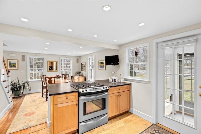 kitchen with dark countertops, plenty of natural light, stainless steel gas range oven, and recessed lighting