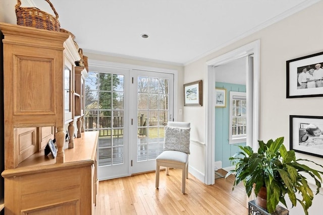 living area with light wood-type flooring, baseboards, and crown molding