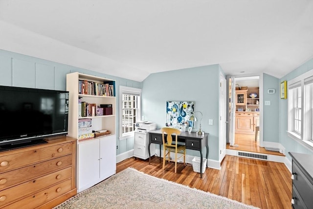 interior space with lofted ceiling, light wood-style flooring, visible vents, and baseboards