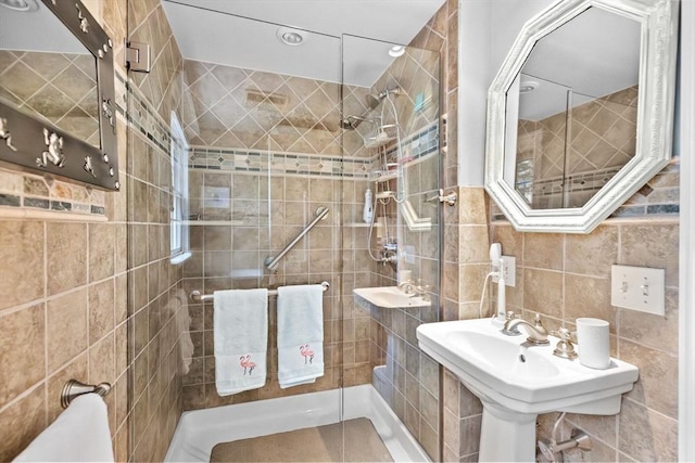 full bathroom with a sink, a shower stall, and tile walls