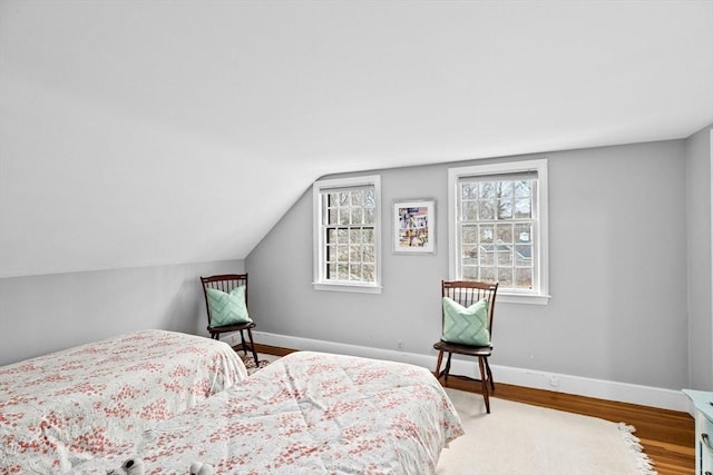 bedroom with lofted ceiling, wood finished floors, and baseboards