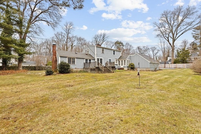 back of property featuring a deck, a yard, a chimney, and fence