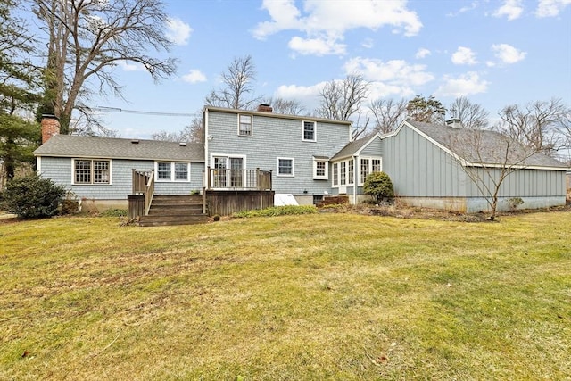 back of property with a deck, a lawn, and a chimney