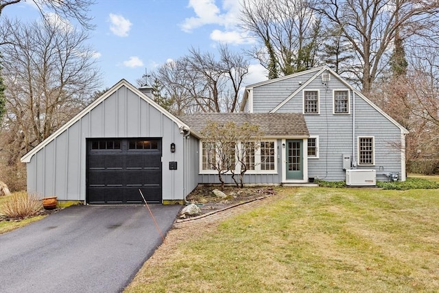 view of front of property with roof with shingles, an attached garage, board and batten siding, a front yard, and driveway