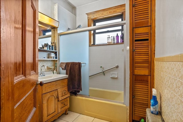 bathroom featuring tile walls, combined bath / shower with glass door, vanity, and tile patterned flooring