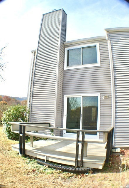 back of property featuring a chimney and a deck