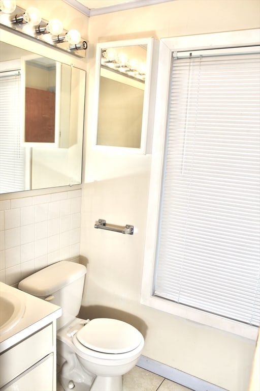 bathroom with tile walls, vanity, toilet, and tile patterned flooring