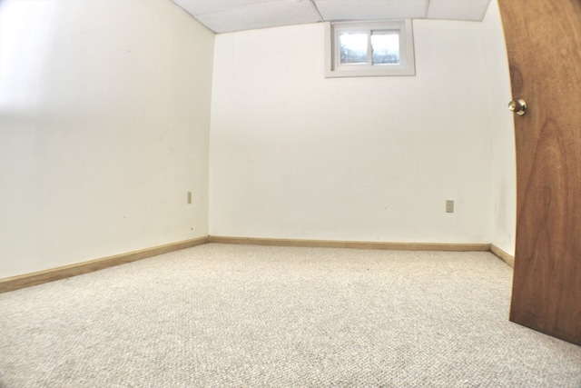 below grade area with a paneled ceiling, carpet, and baseboards