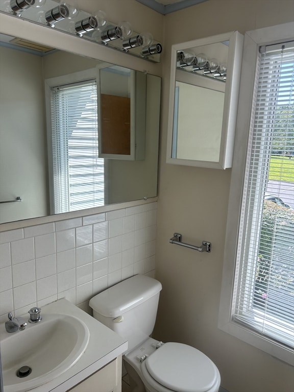 bathroom with tile walls, vanity, and toilet