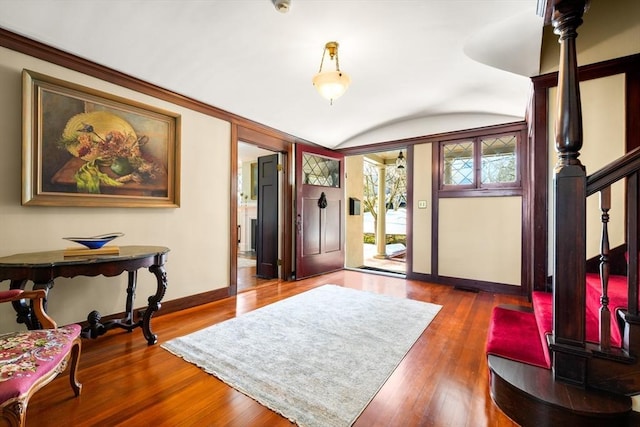 foyer with baseboards, vaulted ceiling, hardwood / wood-style floors, and stairs