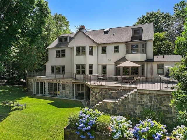 back of house featuring a chimney, stucco siding, a lawn, stairway, and stone siding