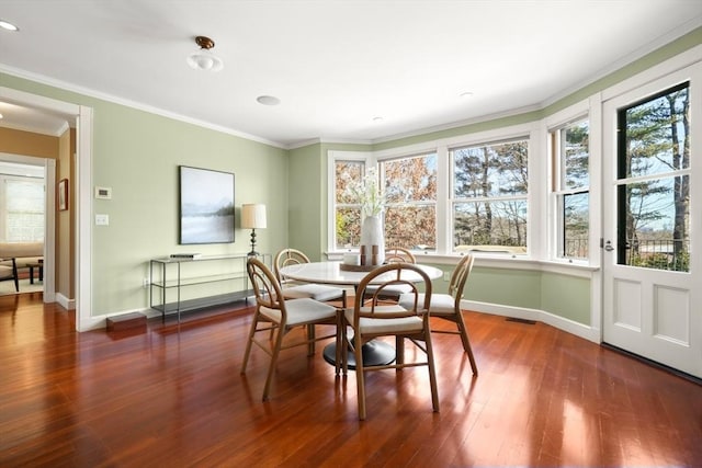 dining space with crown molding, baseboards, and wood finished floors