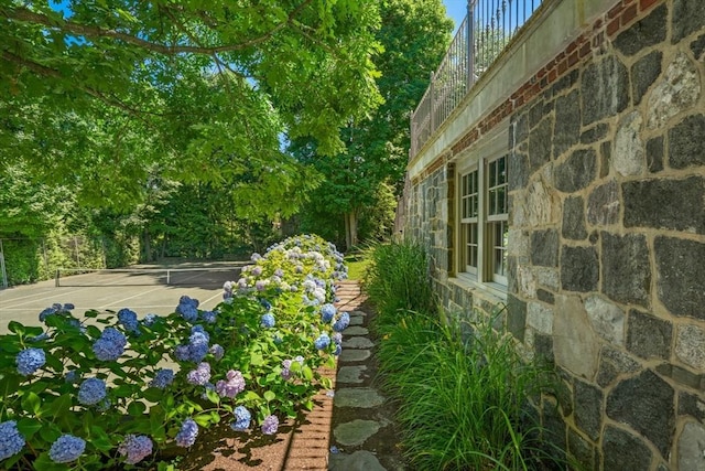 view of yard with a tennis court and fence