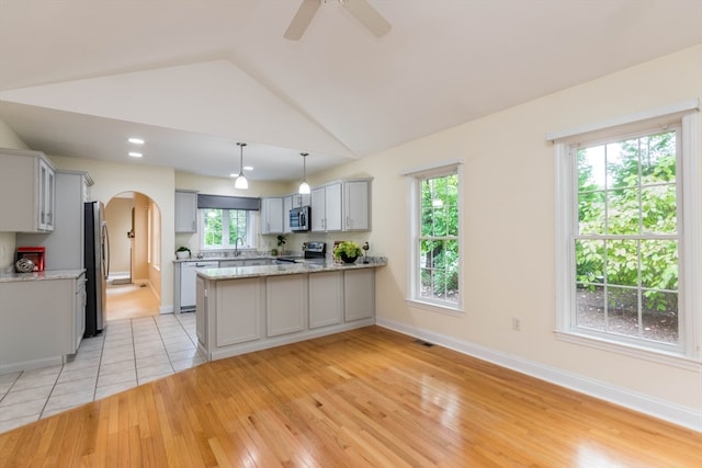 kitchen featuring lofted ceiling, gray cabinets, light wood-type flooring, appliances with stainless steel finishes, and kitchen peninsula