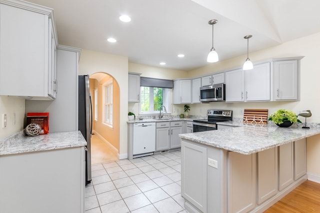 kitchen with hanging light fixtures, appliances with stainless steel finishes, light tile patterned flooring, light stone counters, and kitchen peninsula