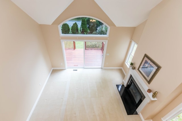 unfurnished living room with light colored carpet and high vaulted ceiling