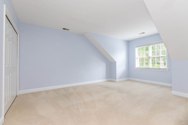 additional living space featuring light colored carpet and vaulted ceiling