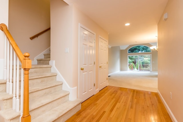 stairway with hardwood / wood-style floors and an inviting chandelier