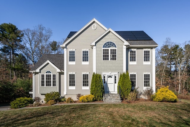 colonial inspired home featuring solar panels and a front yard