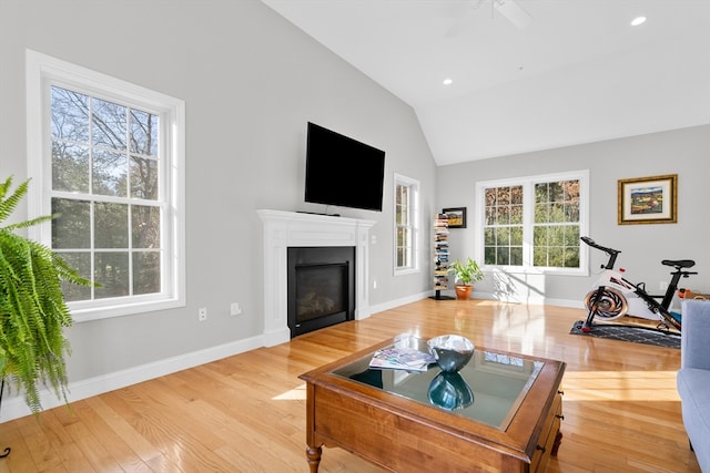 living room with plenty of natural light, ceiling fan, light hardwood / wood-style flooring, and vaulted ceiling