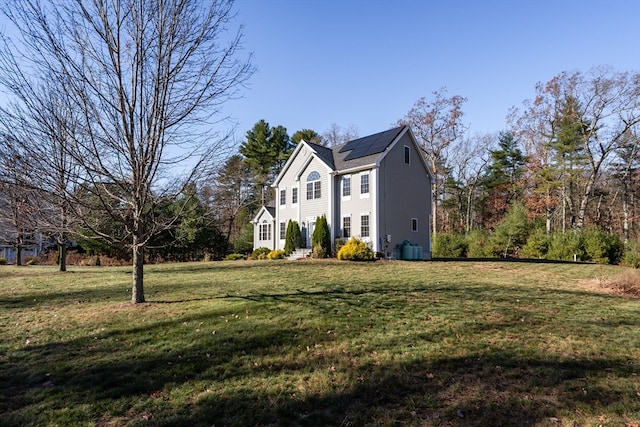 view of side of property featuring solar panels and a yard