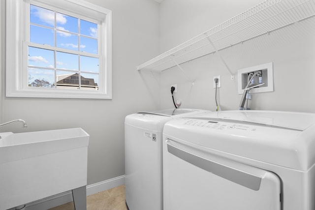 laundry area featuring light tile patterned floors, separate washer and dryer, and sink