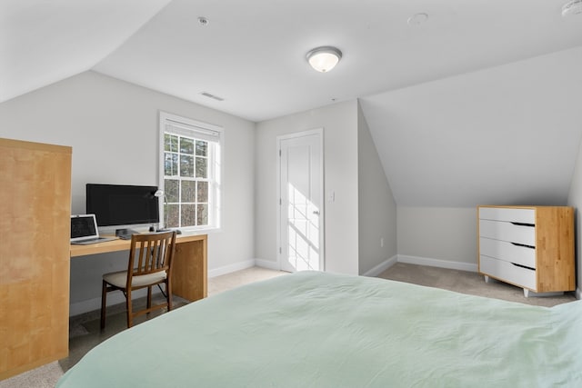 bedroom with light colored carpet, built in desk, and vaulted ceiling