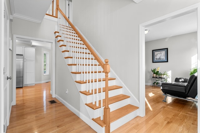 stairs featuring hardwood / wood-style floors and ornamental molding