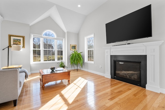 living room with light hardwood / wood-style floors, high vaulted ceiling, and plenty of natural light