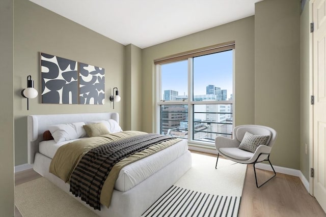 1 Nassau St Unit 2105, Boston, MA 02111 - bedroom featuring a city view, light wood-style flooring, and baseboards