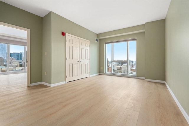 1 Nassau St Unit 2105, Boston, MA 02111 - unfurnished bedroom with a closet, light wood-style flooring, a view of city, and baseboards
