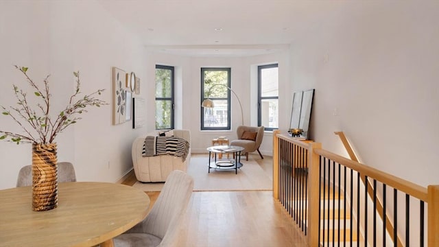 sitting room with light wood-type flooring, baseboards, and an upstairs landing