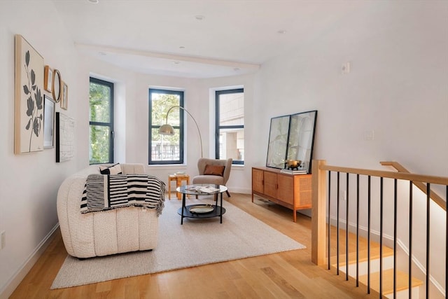 living area featuring an upstairs landing, baseboards, and wood finished floors