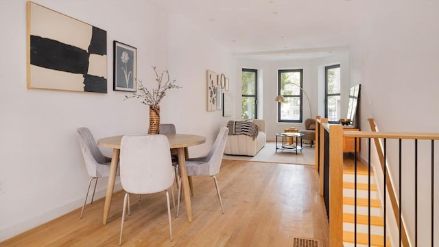 dining space with light wood-type flooring, visible vents, and baseboards