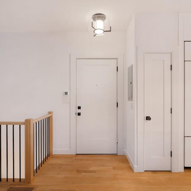 doorway to outside featuring baseboards, electric panel, and light wood-style floors